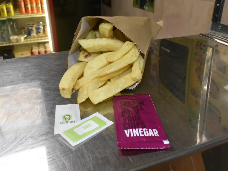 A bag of chips with vinegar sachets on the counter